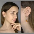 Model wearing Genuine Baltic honey amber Gemma drop earrings in 925 sterling silver fish hook design, showing elegant oval amber stones and lightweight dangle fit
