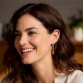 Woman wearing gold plated 925 sterling silver Baltic honey amber lever back drop earrings, showing natural honey-colored amber stones in a lifestyle setting