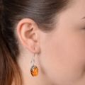 Model wearing genuine Baltic amber drop earring in 925 sterling silver, handcrafted in Poland with natural honey amber stone