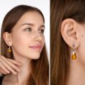 Model wearing genuine Baltic honey amber teardrop earrings in 925 sterling silver, showing natural amber inclusions and elegant lightweight drop design