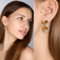 Model wearing genuine Baltic honey amber “Sun” earrings in 925 sterling silver—two-tone amber stud with dangling sunburst charm, shown in face view and close-up on ear.