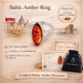 Promotional graphic for a Baltic amber ring in sterling silver, featuring a large amber ring image, authenticity certificate badge, Polish flag and city backdrop, product feature list, certificate card, branded gift pouch, and the text “Certified Baltic Amber (Succinite).