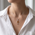 Woman wearing the Baltic Honey Amber Pendant Necklace in Sterling Silver on a delicate silver chain, showcasing genuine honey Baltic amber in an elegant luxury jewelry lifestyle setting.