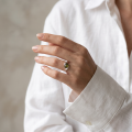 Woman wearing the Estelle Baltic Green Amber Ring in Sterling Silver, showcasing a genuine green Baltic amber gemstone and polished 925 sterling silver in an elegant luxury jewelry lifestyle setting.