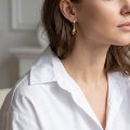 Woman wearing the Karolina Baltic Honey Amber Earrings in Sterling Silver, showcasing genuine honey Baltic amber and polished 925 sterling silver in an elegant luxury jewelry lifestyle setting.