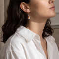 Woman wearing the Baltic Honey Amber Oval Drop Earrings in Sterling Silver, showcasing genuine honey Baltic amber and polished 925 sterling silver in an elegant luxury jewelry lifestyle setting.