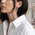 Woman wearing the Nadia Baltic Honey Amber Earrings in Sterling Silver, showcasing genuine honey Baltic amber and polished 925 sterling silver in an elegant luxury jewelry lifestyle setting.