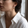Woman wearing the Tricia Baltic Honey Amber Earrings in Sterling Silver, showcasing genuine honey Baltic amber and polished 925 sterling silver in an elegant luxury jewelry lifestyle setting.