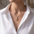 Woman wearing the Julianne Baltic Honey Amber Pendant in Sterling Silver on a delicate silver chain, showcasing genuine honey Baltic amber in an elegant luxury jewelry lifestyle setting.