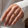 Woman wearing the Clara Baltic Honey Amber Ring in Sterling Silver, showcasing a genuine honey Baltic amber gemstone and polished 925 sterling silver in an elegant luxury jewelry lifestyle setting.