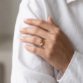 Woman wearing the Estelle Baltic Honey Amber Ring in Sterling Silver, showcasing a genuine honey Baltic amber gemstone and polished 925 sterling silver in an elegant luxury jewelry lifestyle setting.