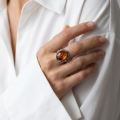 Woman wearing the Baltic Honey Amber Oval Ring in Sterling Silver, showcasing a genuine oval honey Baltic amber gemstone and polished 925 sterling silver in an elegant luxury jewelry lifestyle setting.