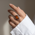 Woman wearing the Baltic Honey Amber Oval Classic Ring in Sterling Silver, showcasing a genuine oval honey Baltic amber gemstone and polished 925 sterling silver in an elegant luxury jewelry lifestyle setting.