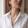 Woman wearing the Emma Baltic Green Amber Drop Earrings in Sterling Silver, showcasing genuine green Baltic amber and polished 925 sterling silver in an elegant luxury jewelry lifestyle setting.