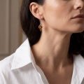 Woman wearing the Charlotte Baltic Honey Amber Earrings in Sterling Silver, showcasing genuine honey Baltic amber and polished 925 sterling silver in an elegant luxury jewelry lifestyle setting.