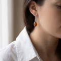 Woman wearing the Milena Baltic Honey Amber Earrings in Sterling Silver, showcasing genuine honey Baltic amber and polished 925 sterling silver in an elegant luxury jewelry lifestyle setting.