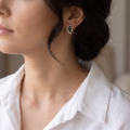 Woman wearing the Harper Baltic Green Amber Earrings in Sterling Silver, showcasing genuine green Baltic amber and polished 925 sterling silver in an elegant luxury jewelry lifestyle setting.