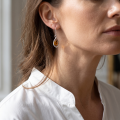 Woman wearing the Penelope Baltic Honey Amber Earrings in Sterling Silver, showcasing genuine honey Baltic amber and polished 925 sterling silver in an elegant luxury jewelry lifestyle setting.