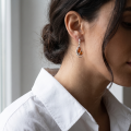 Woman wearing the Ava Baltic Honey Amber Earrings in Sterling Silver, showcasing genuine honey Baltic amber and polished 925 sterling silver in an elegant luxury jewelry lifestyle setting.