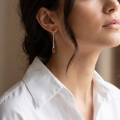 Woman wearing the Ariana Baltic Honey Amber Earrings in Sterling Silver, showcasing genuine honey Baltic amber and polished 925 sterling silver in an elegant luxury jewelry lifestyle setting.