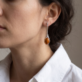 Woman wearing the Maggie Baltic Honey Amber Earrings in Sterling Silver, showcasing genuine honey Baltic amber and polished 925 sterling silver in an elegant luxury jewelry lifestyle setting.