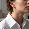 Woman wearing the Genesis Baltic Honey Amber Earrings in Sterling Silver, showcasing genuine honey Baltic amber and polished 925 sterling silver in an elegant luxury jewelry lifestyle setting.