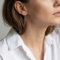 Woman wearing the Aurora Baltic Honey Amber Earrings in Sterling Silver, showcasing genuine honey Baltic amber and polished 925 sterling silver in an elegant luxury jewelry lifestyle setting.