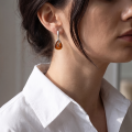 Woman wearing the Yvonne Baltic Honey Amber Earrings in Sterling Silver, showcasing genuine honey Baltic amber and polished 925 sterling silver in an elegant luxury jewelry lifestyle setting.