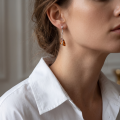 Woman wearing the Triangle Baltic Honey Amber Earrings in Sterling Silver, showcasing genuine honey Baltic amber and polished 925 sterling silver in an elegant luxury jewelry lifestyle setting.