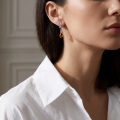 Woman wearing the Daria Baltic Honey Amber Earrings in Sterling Silver, showcasing genuine honey Baltic amber and polished 925 sterling silver in an elegant luxury jewelry lifestyle setting.