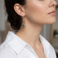 Woman wearing the Chiara Baltic Green Amber Earrings in Sterling Silver, showcasing genuine green Baltic amber and polished 925 sterling silver in an elegant luxury jewelry lifestyle setting.