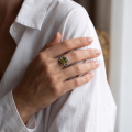 Woman wearing the GIA Certified Georgine Baltic Green Amber Ring in Sterling Silver, showcasing genuine green Baltic amber and polished 925 sterling silver in an elegant luxury jewelry lifestyle setting.