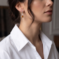 Woman wearing the Zara Baltic Honey Amber Earrings in Sterling Silver, showcasing genuine honey Baltic amber and polished 925 sterling silver in an elegant luxury jewelry lifestyle setting.