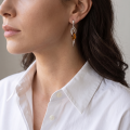 Woman wearing the Martha Baltic Honey Amber Earrings in Sterling Silver, showcasing genuine honey Baltic amber and polished 925 sterling silver in an elegant luxury jewelry lifestyle setting.