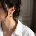 Woman wearing the Maisie Baltic Honey Amber Earrings in Sterling Silver, showcasing genuine honey Baltic amber and polished 925 sterling silver in an elegant luxury jewelry lifestyle setting.