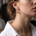 Woman wearing the Serenity Baltic Honey Amber Earrings in Sterling Silver, showcasing genuine honey Baltic amber and polished 925 sterling silver in an elegant luxury jewelry lifestyle setting.