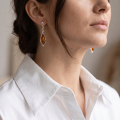 Woman wearing the Neveah Baltic Honey Amber Earrings in Sterling Silver, showcasing genuine honey Baltic amber and polished 925 sterling silver in an elegant luxury jewelry lifestyle setting.