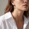 Woman wearing the Baltic Honey Amber Drop Stud Earrings in Sterling Silver, showcasing genuine honey Baltic amber and polished 925 sterling silver in an elegant luxury jewelry lifestyle setting.