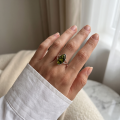 Woman wearing the Autumn Baltic Green Amber Ring in Sterling Silver, showcasing genuine green Baltic amber and polished 925 sterling silver in an elegant luxury jewelry lifestyle setting.