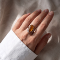 Woman wearing the Micaela Baltic Honey Amber Oval Ring in Sterling Silver, showcasing genuine oval honey Baltic amber and polished 925 sterling silver in an elegant luxury jewelry lifestyle setting.