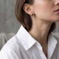 Woman wearing the Emily Baltic Honey Amber Earrings in Sterling Silver, showcasing genuine honey Baltic amber and polished 925 sterling silver in an elegant luxury jewelry lifestyle setting.