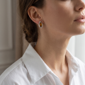 Woman wearing the Harper Baltic Honey Amber Earrings in Sterling Silver, showcasing genuine honey Baltic amber and polished 925 sterling silver in an elegant luxury jewelry lifestyle setting.