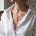 Woman wearing the Baltic Amber Cross Pendant in Sterling Silver, showcasing genuine Baltic amber and polished 925 sterling silver in an elegant luxury jewelry lifestyle setting.