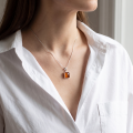 Woman wearing the Lottie Baltic Honey Amber Pendant Necklace in Sterling Silver, showcasing genuine honey Baltic amber and polished 925 sterling silver in an elegant luxury jewelry lifestyle setting.