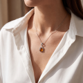 Woman wearing the Dawn Baltic Honey Amber Pendant in Sterling Silver, showcasing genuine honey Baltic amber and polished 925 sterling silver in an elegant luxury jewelry lifestyle setting.