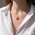 Woman wearing the GIA Certified Baltic Honey Amber Fern Pendant Necklace in Sterling Silver, showcasing genuine honey Baltic amber and polished 925 sterling silver in an elegant luxury jewelry lifestyle setting.