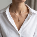 Woman wearing the Meadow Baltic Honey Amber Pendant in Sterling Silver, showcasing genuine honey Baltic amber and polished 925 sterling silver in an elegant luxury jewelry lifestyle setting.