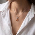 Woman wearing the Sunny Baltic Honey Amber Pendant in Sterling Silver, showcasing genuine honey Baltic amber and polished 925 sterling silver in an elegant luxury jewelry lifestyle setting.