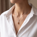 Woman wearing the Misty Baltic Honey Amber Pendant in Sterling Silver, showcasing genuine honey Baltic amber and polished 925 sterling silver in an elegant luxury jewelry lifestyle setting.