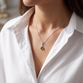 Woman wearing the Raine Baltic Honey Amber Pendant in Sterling Silver, showcasing genuine honey Baltic amber and polished 925 sterling silver in an elegant luxury jewelry lifestyle setting.